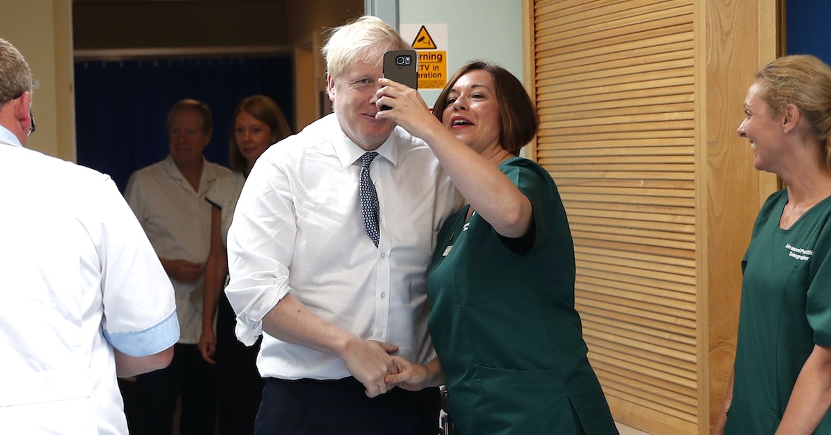 Prime Minister Boris Johnson poses for a photo with a member of staff during a visit to Pilgrim Hospital in Boston, Lincolnshire, to announce the government's NHS spending pledge of 1.8 billion.